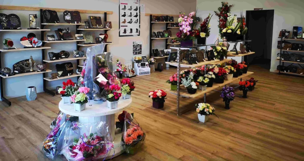 Intérieur spacieux Magasin Vergnaud : plaques deuil, fleurs artificielles exposées.